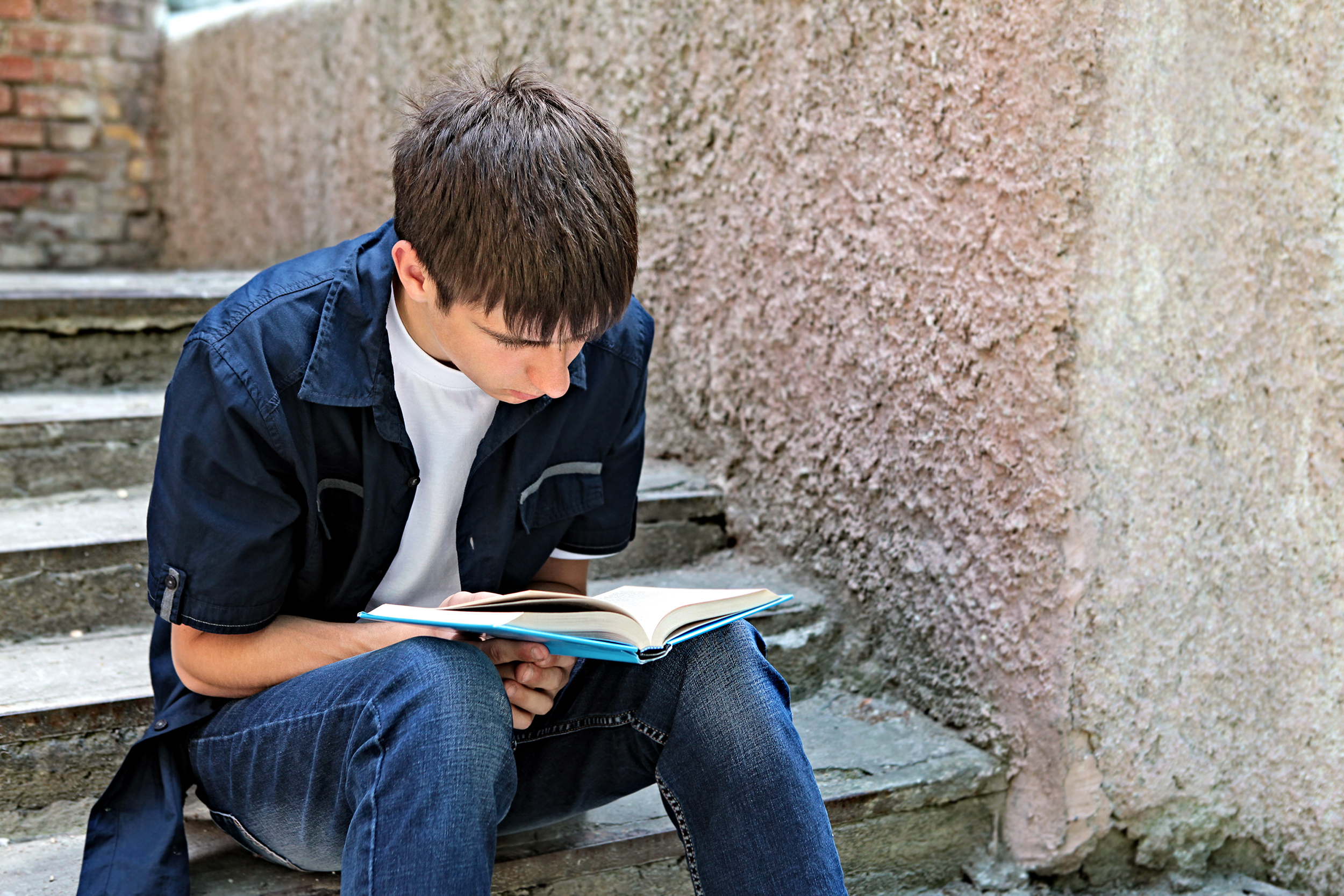 male-student-on-step-reading-shutterstock